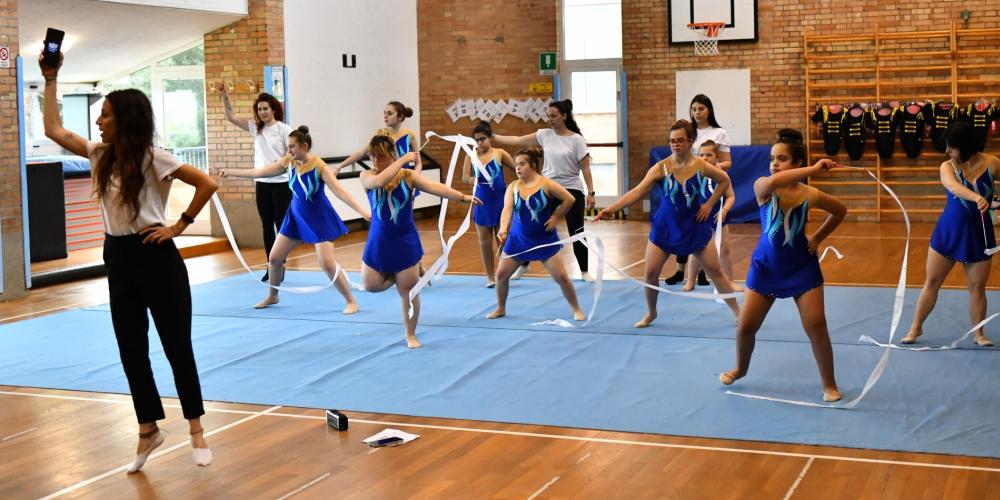 Ginnaste in blu danzano con nastri, energia e concentrazione in palestra.